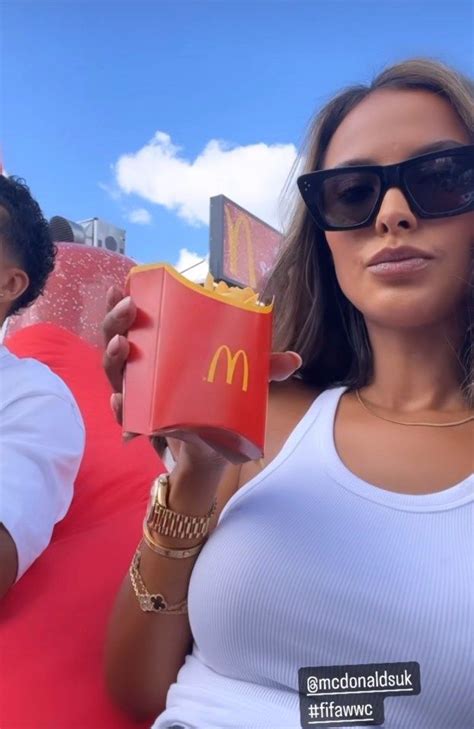 A Woman In Sunglasses Holding Up A Mcdonald S Cup With A Man Standing