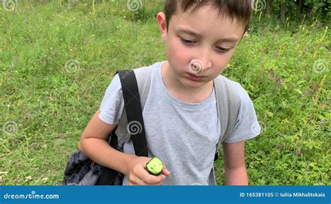 A Portrait Of A Hungry Preteen Boy Walking Through A Green Field