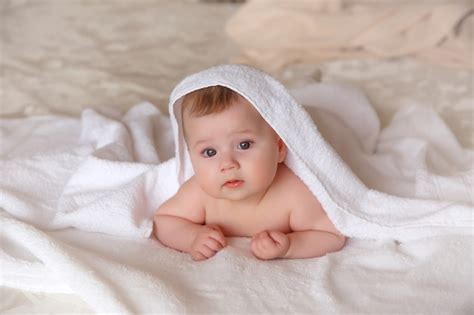 Premium Photo Baby Is Covered With A Towel After Bathing Lying On The Bed In The Bedroom