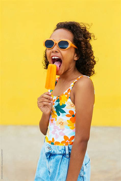 Happy Ethnic Girl Licking Ice Pop By Bonninstudio