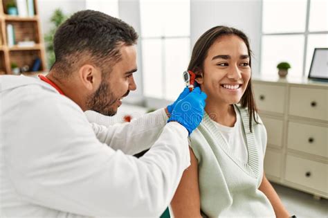 Doctor Examining Latin Woman Ear Using Otoscope At Clinic Stock Photo