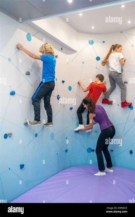 Children Climbing Special Wall And Woman Helping Stock Photo Alamy