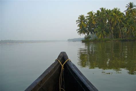 There Is A Boat In The Water With Palm Trees Behind It