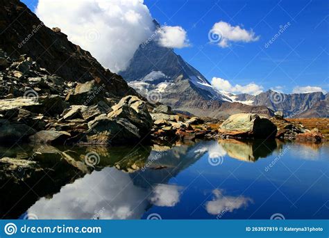 A Mountain Matterhorn View Partially Covered By Clouds And Reflected In