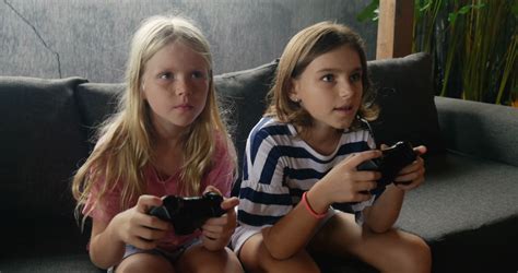 Two Happy Smiling Young Girls Playing A Video Game Together And Talking