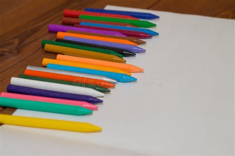 Colorful Crayons With A White Blank Sheet Of Paper On A Wooden B Stock