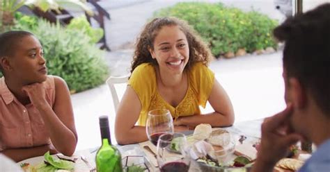 Happy Biracial Woman Laughing With Friends At Dinner Party On Patio