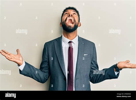 Handsome Hispanic Man With Beard Wearing Business Suit And Tie Crazy And Mad Shouting And