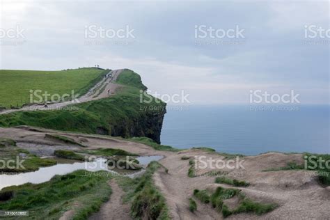 アイルランドのモハーの美しい崖緑のフィールドパスと海写真を撮る遠くの人々 ひらめきのストックフォトや画像を多数ご用意 ひらめき