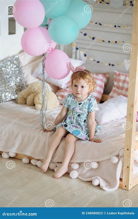 Petite Fille En Robe Bleue Est Assise Sur Le Lit Image Stock Image