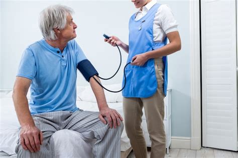 Nurse Checking Blood Pressure Of Senior Man At Home Premium Photo