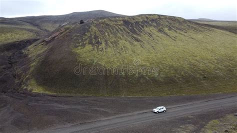 Drone Shot Of A Car Going By A Green Moss Covered Volcanic Mountain And
