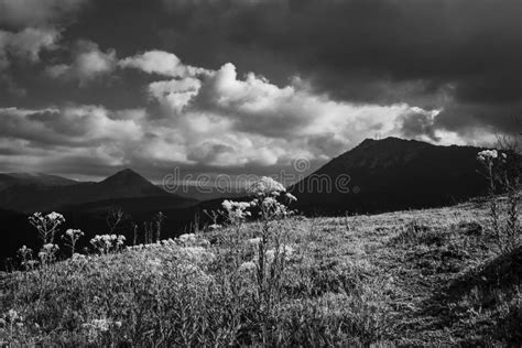 A Black And White Mountain Landscape With Dramatic Sky And High