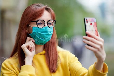 A Girl With Glasses In A Medical Mask Adjusts It With Her Hand Holds A