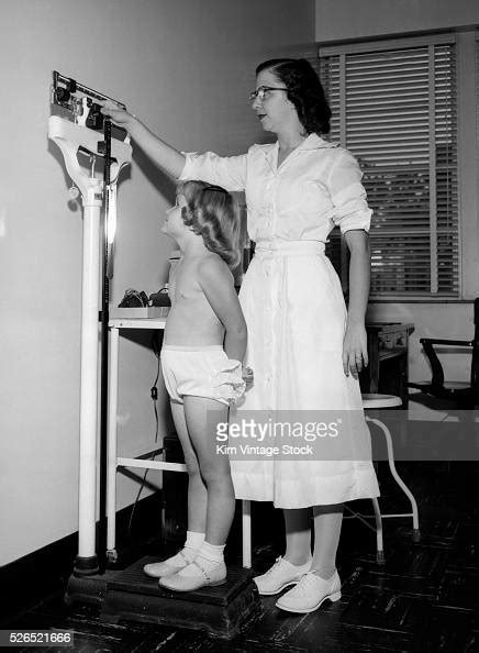 A Nurse Measures Height And Weight For A Young Girl During A Medical
