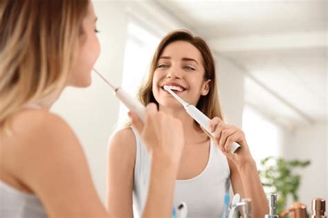 Young Beautiful Woman With Toothbrush Near Mirror In Bathroom Personal