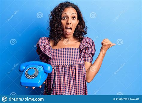 Middle Age Beautiful Woman Holding Vintage Telephone Pointing Thumb Up