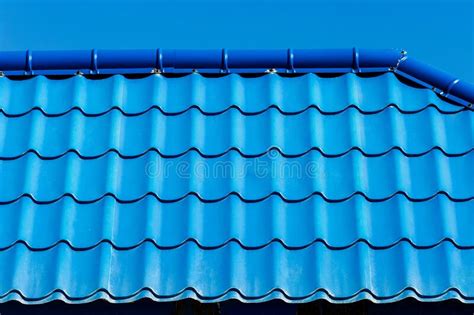 Blue Tiles Of The Roof Of A House Or Building Against The Cloud Sky