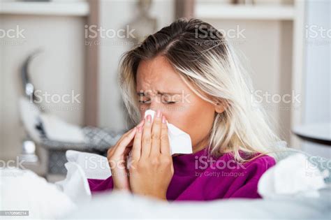 아픈 여자독감여자는 감기에 걸렸습니다 조직으로 재채기 두통 바이러스 의약품 젊은 여자 감염 에 감기 불고 그녀의 코 에 손수건 소파에 앉아 두통을 가진 아픈 여자 감기와