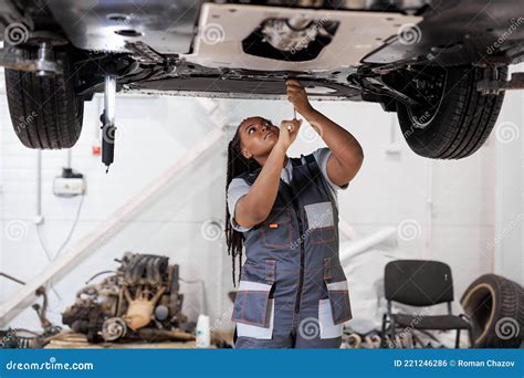 African Female Auto Mechanic Fixing Car Mechanic Repairing Car On Lift