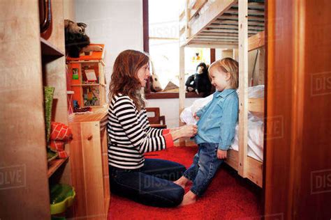 Mother Dressing Son In Bedroom Stock Photo Dissolve