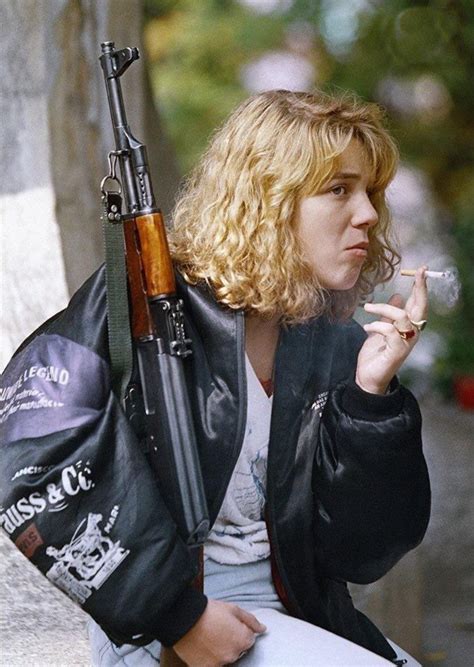 A Bosnian Girl Holding An Ak 47 Rifle Smokes A Cigarette As She Waits