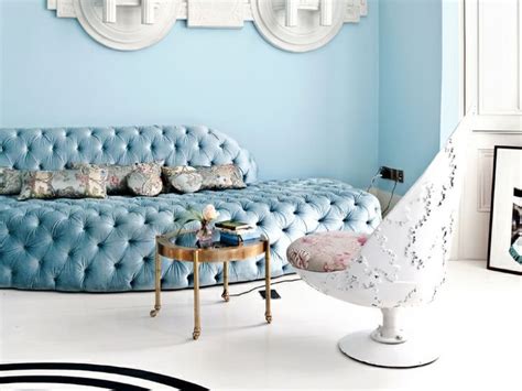 A Living Room With A Blue Couch And Two Mirrors On The Wall Above Its
