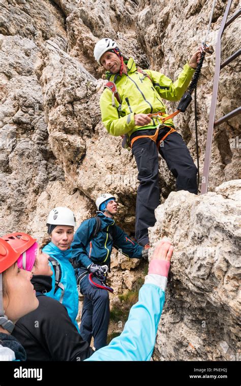 A Male Mountain Guide Instructs Young Climbers At The Start Of A Steep