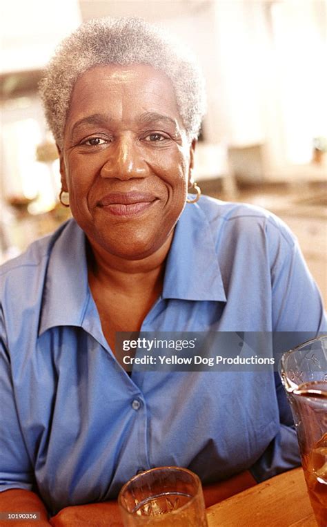 Mature Woman Sitting In Kitchen Close Up Portrait High Res Stock Photo