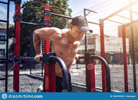 Strong Muscular Man Doing Push Ups On Uneven Bars In Outdoor Street Gym