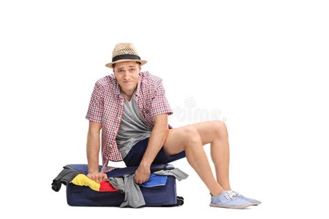 Sad Male Tourist Sitting On Top Of A Packed Suitcase Stock Image