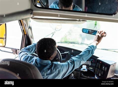 Mature African American Driver Adjusting Back View Mirror At Bus Stock