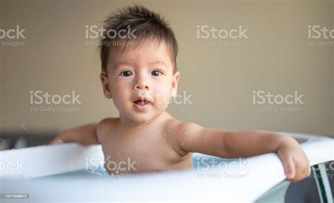 Adorable Baby Boy Having A Bath In A Small Baby Tub In The Living Room