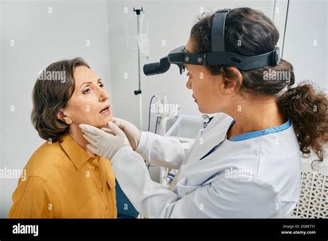 ent doctor doing throat exam of a senior woman mature patient opened her mouth to throat check