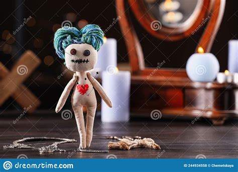 Female Voodoo Doll With Pins In Heart And Ceremonial Items On Wooden
