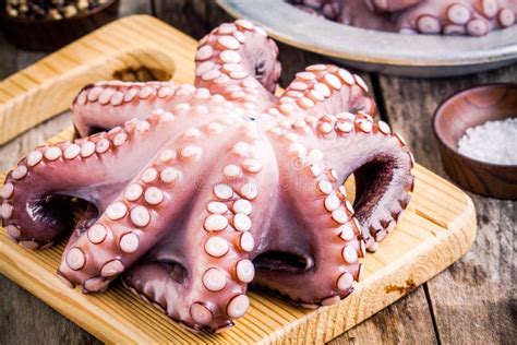 Whole Fresh Raw Octopus On Cutting Board With Sea Salt Stock Photo