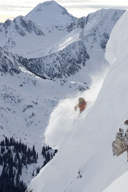 Professional Woman Skier In Powder On Steep Alpine Slope With Mt McBride Behind Valkyr Range