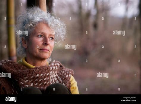 Portrait Of Grey Haired Mature Woman Gazing In Woodland At Dusk Stock