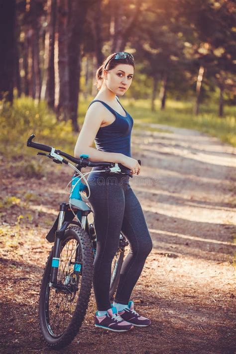Woman Cyclist Rides In The Forest On A Mountain Bike Stock Photo