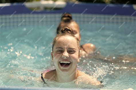 Счастливые дети плавают в бассейне в солнечный летний день летом