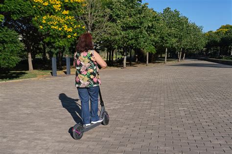Latin Mature Woman Riding Her Electric Kick Scooter Modern
