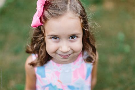 Beautiful Young Girl With A Bow In Her Hair Looking Up At The Camera