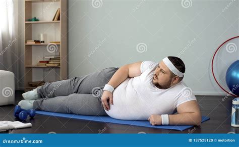 Chubby Man Lying On His Back Watching And Repeating Online Exercises