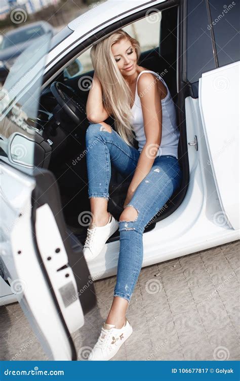 Stylish Young Woman With Long Blond Hair Sitting On The Driver`s Seat Of A Prestigious Car Stock