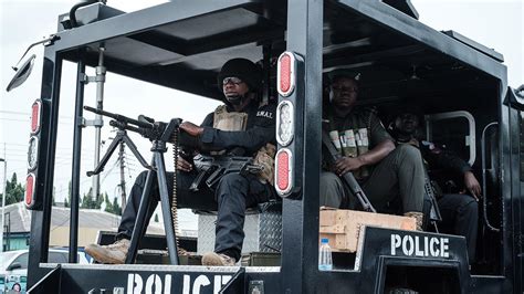 A Nigerian Police Swat Personnel Member Sits Alert With A Machine Gun On A Vehicle Stationed At