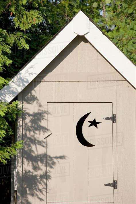 Close Up Of Wooden Outhouse With Crescent Moon And Star Cut Out On Door