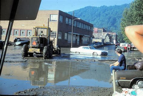 A Man Sitting In The Back Of A Truck On Top Of A Flooded Street Next To
