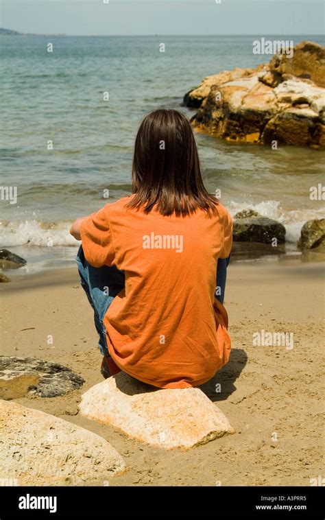 Young Longhaired Boy Sitting Alone On Beach Stock Photo Alamy