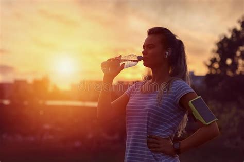 Modern Sporty Woman Drinking Water In Park At Dawn After Intense
