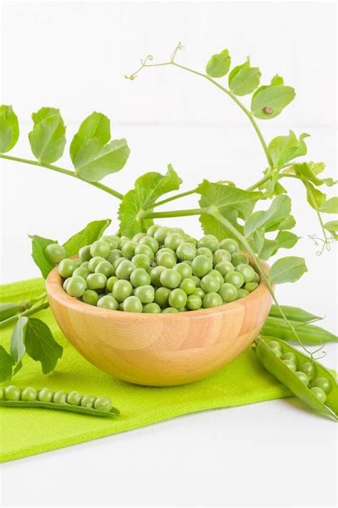 Fresh Green Peas In A Wooden Bowl With Peas Plants Leaves On A Green